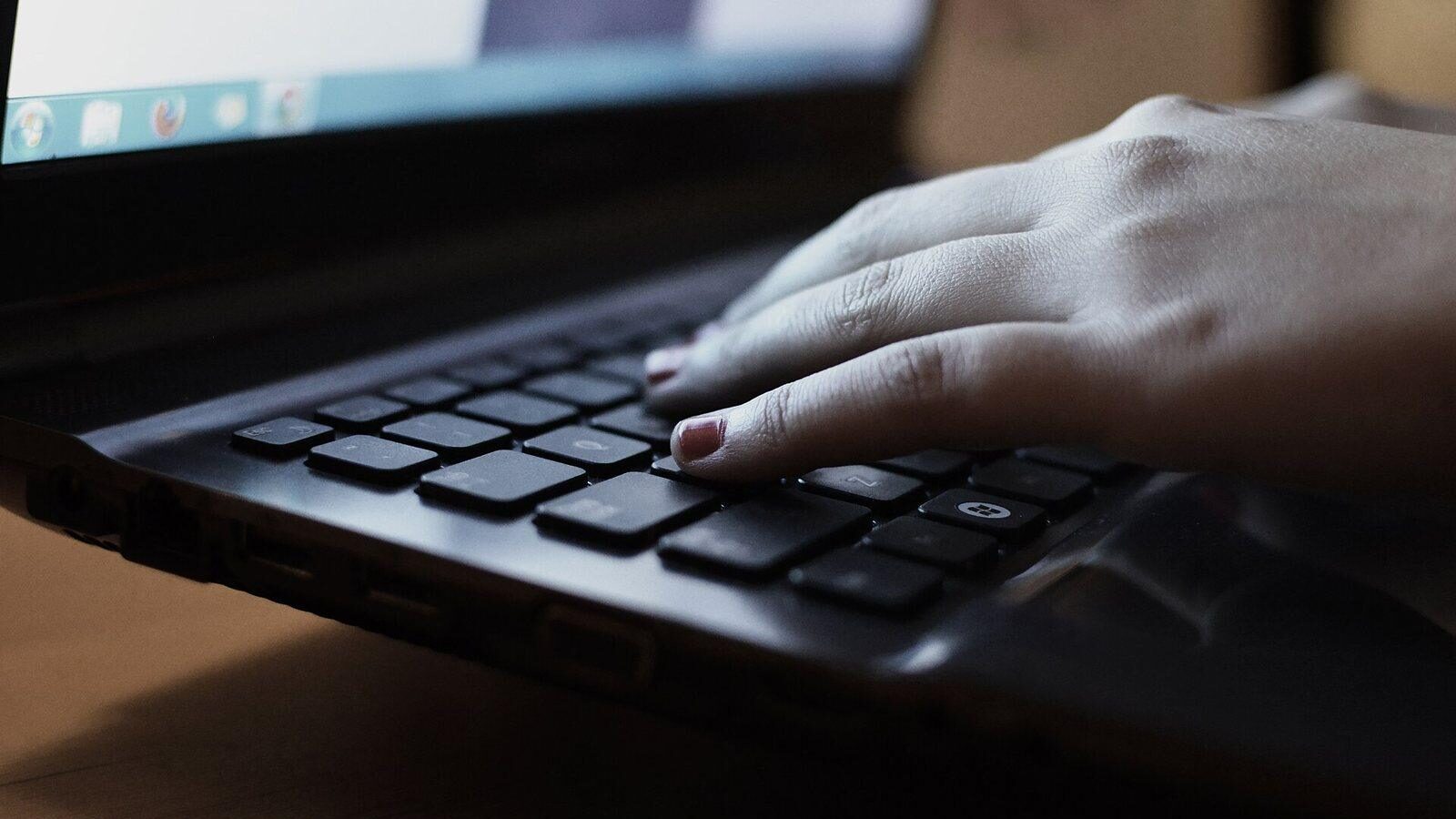 Close-up of hands typing on a laptop keyboard while shopping online
