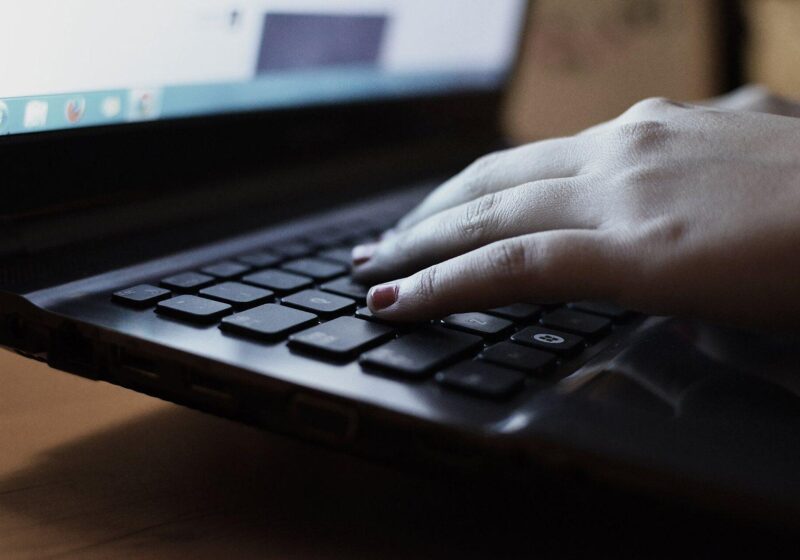 Close-up of hands typing on a laptop keyboard while shopping online
