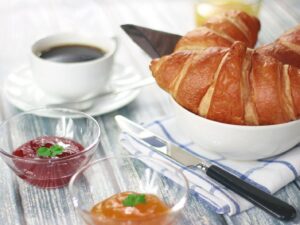 Breakfast table with a cup of coffee, a croissant and small bowls of jam