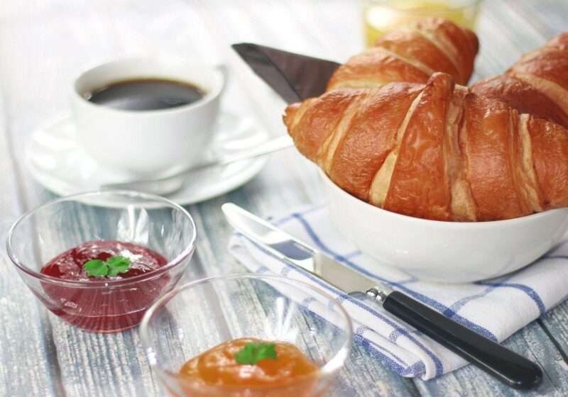 Breakfast table with a cup of coffee, a croissant and small bowls of jam