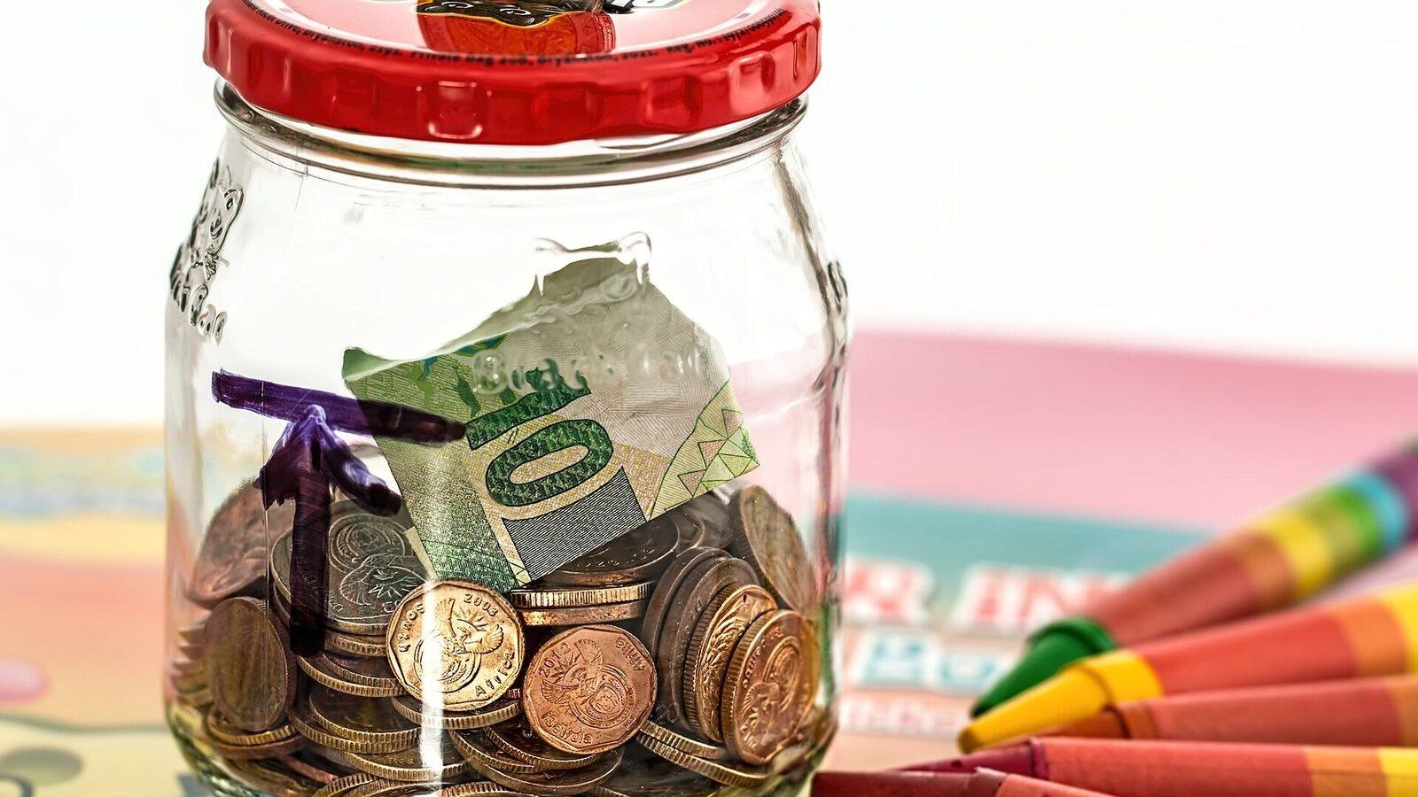 Glass savings jar filled with coins and dollar bills
