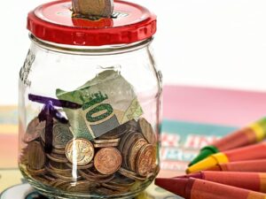 Glass savings jar filled with coins and dollar bills