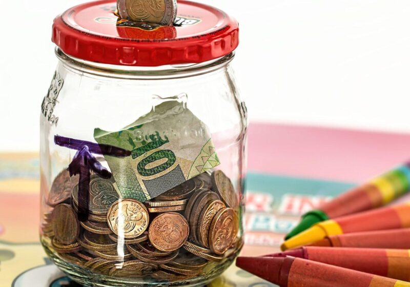 Glass savings jar filled with coins and dollar bills