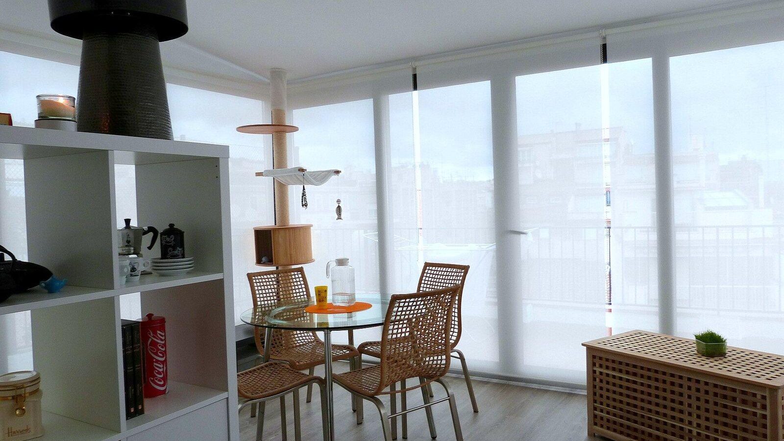 Bright, tidy living space with open shelving, a dining table and large windows