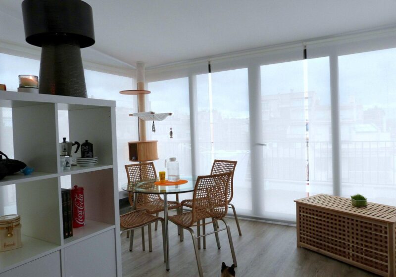 Bright, tidy living space with open shelving, a dining table and large windows
