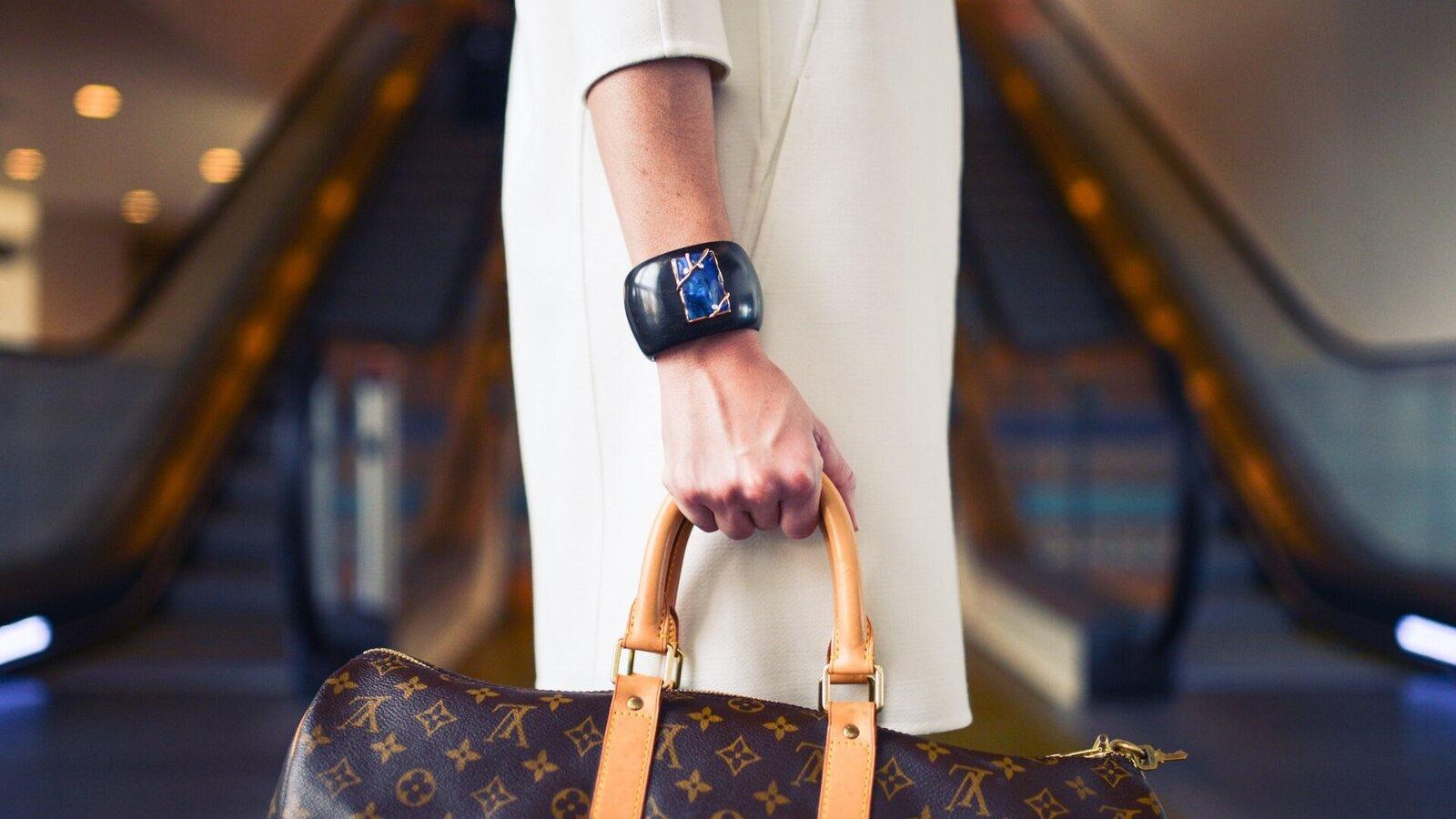 Shopper carrying a leather handbag on a shopping mall escalator
