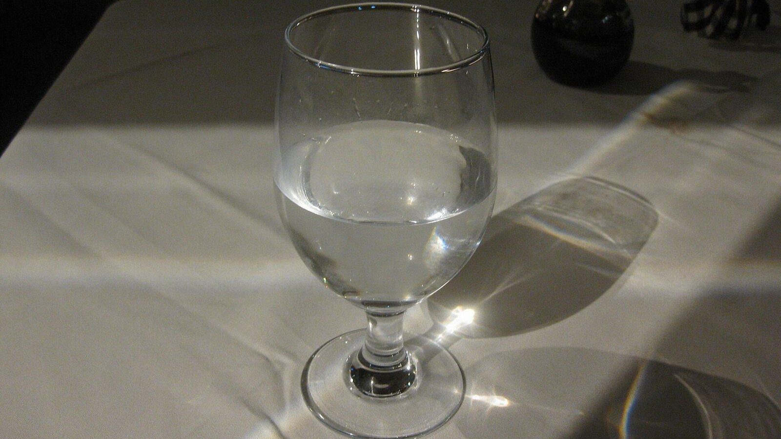 Clear glass of water catching the light on a white tablecloth