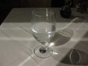 Clear glass of water catching the light on a white tablecloth