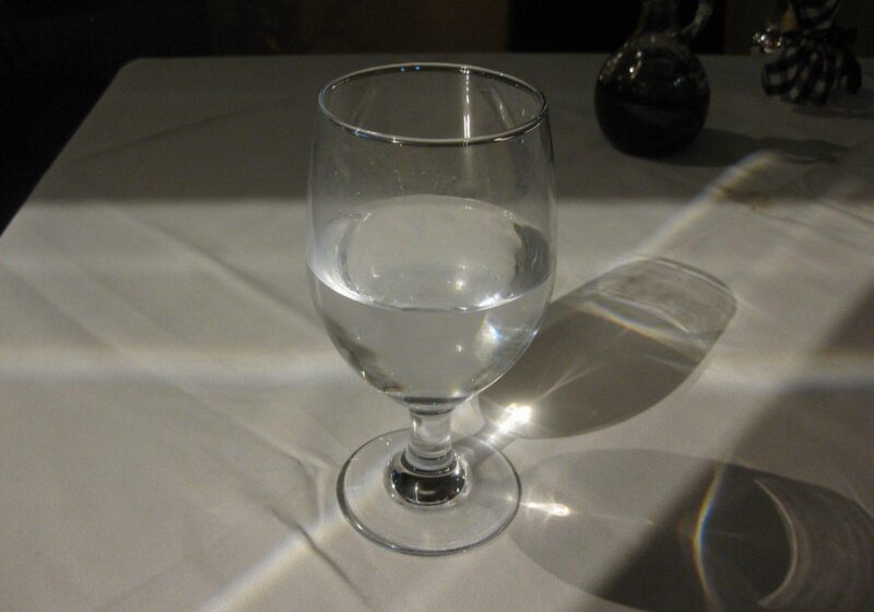 Clear glass of water catching the light on a white tablecloth