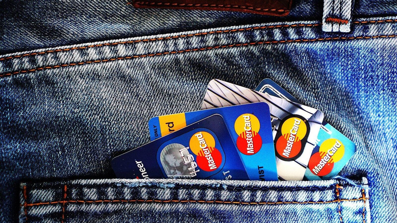 Several credit cards tucked into the back pocket of blue jeans