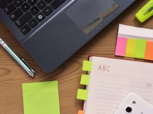 Desk with a laptop, notebook, pen and colorful sticky notes for business planning