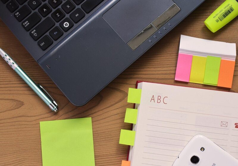 Desk with a laptop, notebook, pen and colorful sticky notes for business planning